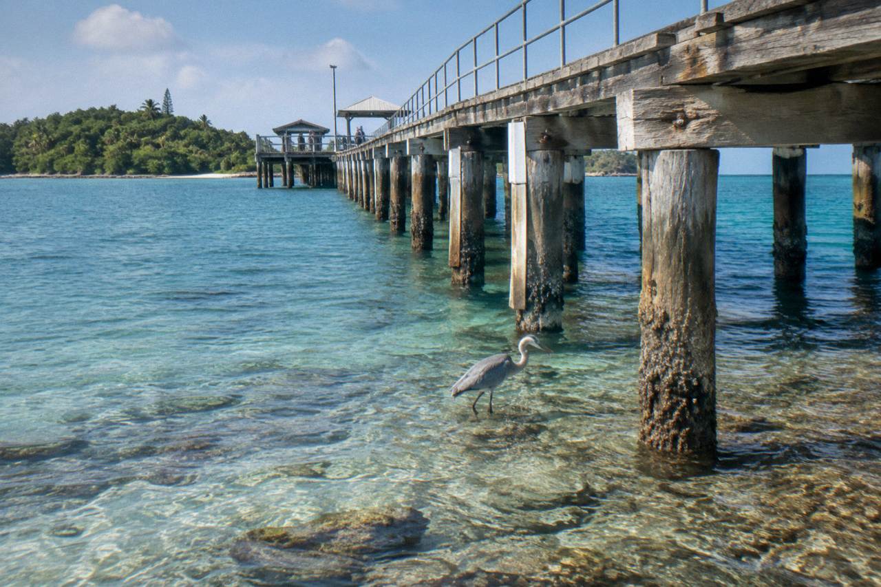 Calm turquoise water and reef shallows surrounding a small tropical island jetty