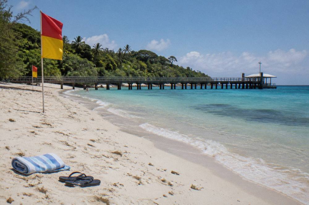 Red and yellow flags marking a patrolled swimming beach beside a jetty