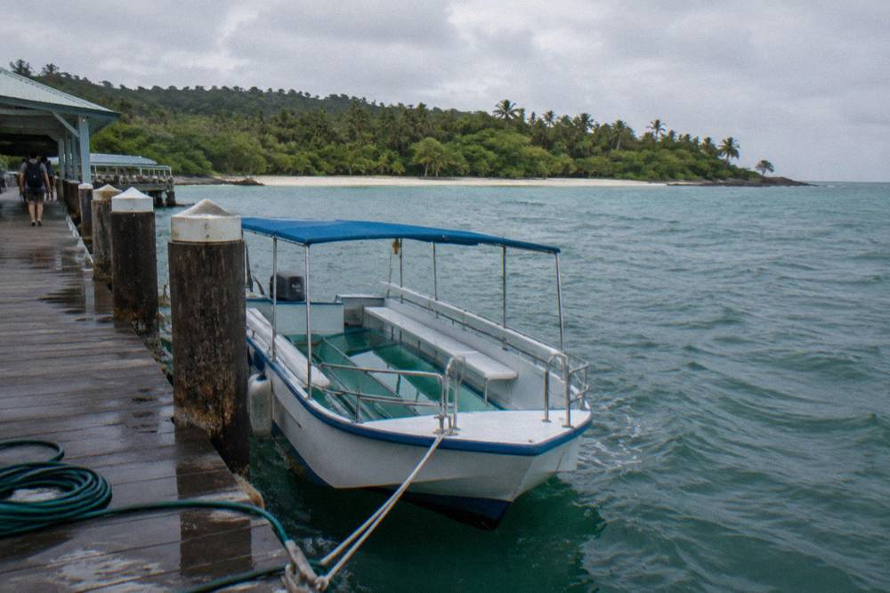 A glass bottom boat moored beside a timber jetty at a tropical island