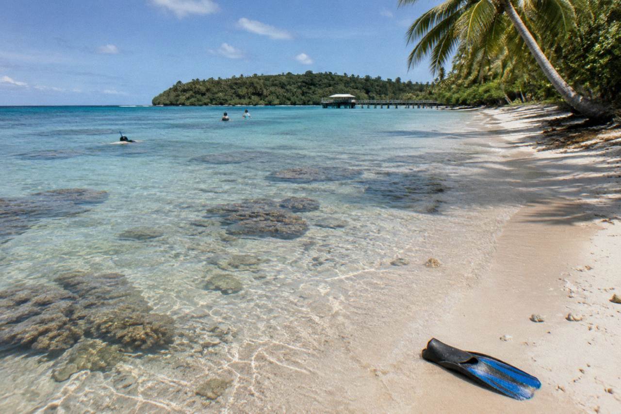 Calm turquoise water over a shallow coral reef beside a tropical island beach