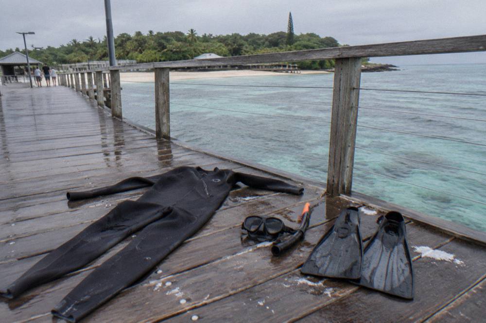 A lycra stinger suit and snorkel gear laid out on a boat deck ready for use