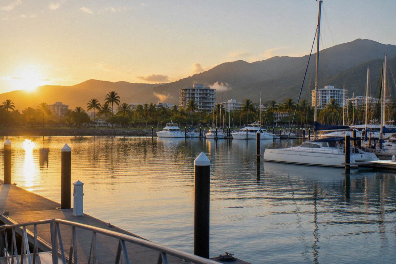 A tropical north Queensland waterfront city skyline beside calm blue water at sunrise