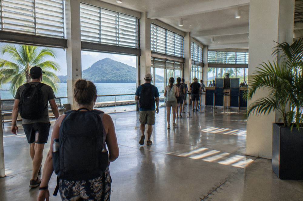 A check-in counter queue inside a ferry terminal with passengers holding tickets and day packs