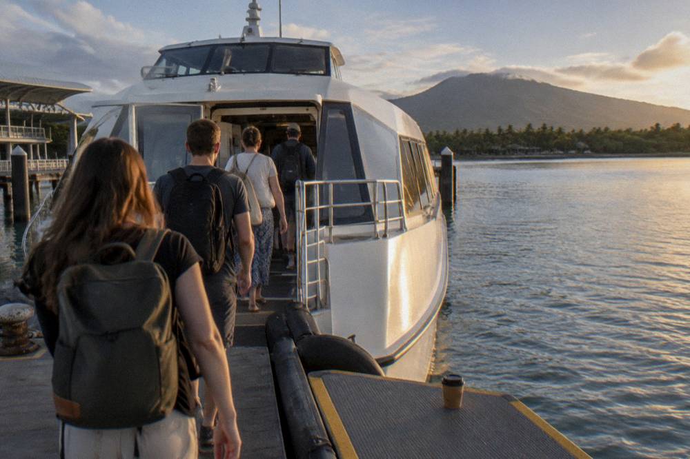 Passengers boarding a fast catamaran at a marina wharf in the early morning light