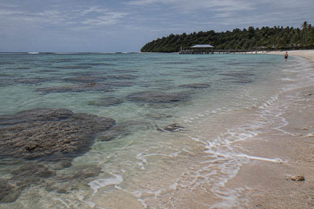 Calm turquoise shallows over coral bommies near a sandy shoreline