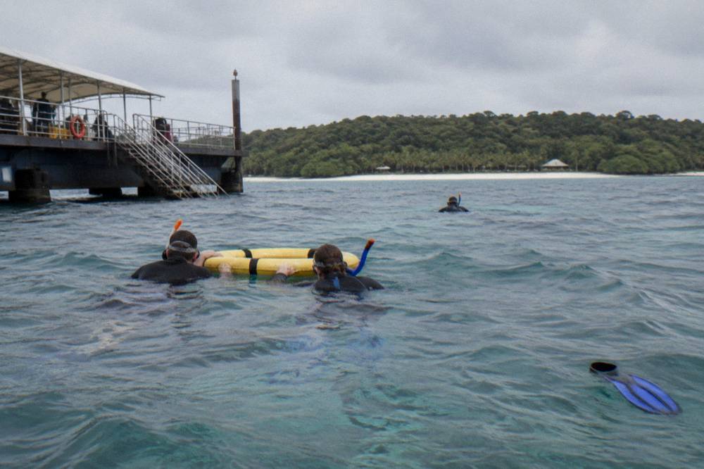 Snorkellers holding onto a flotation ring beside an outer reef pontoon in open water