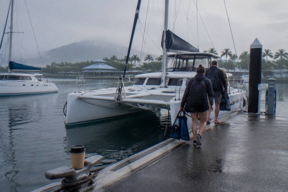 Cairns marina wharf with moored catamarans and passengers boarding in the morning