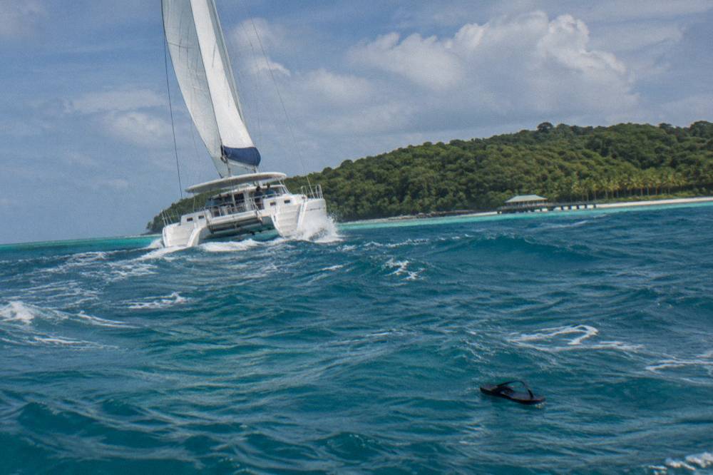 A fast catamaran cruising across open water toward a green island on the horizon