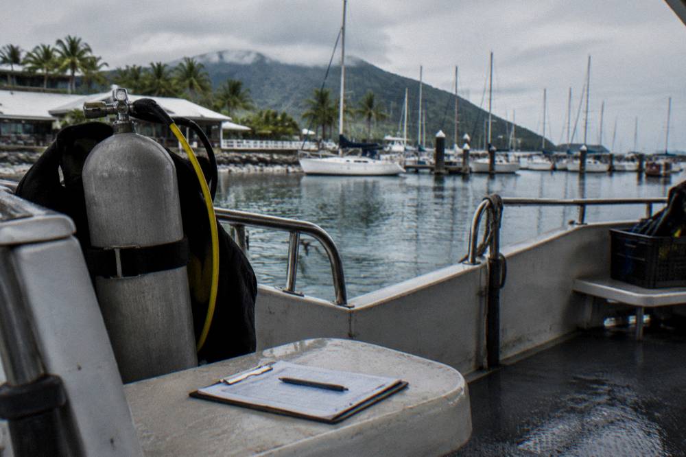 A clipboard medical form resting on a dive boat seat beside a scuba tank