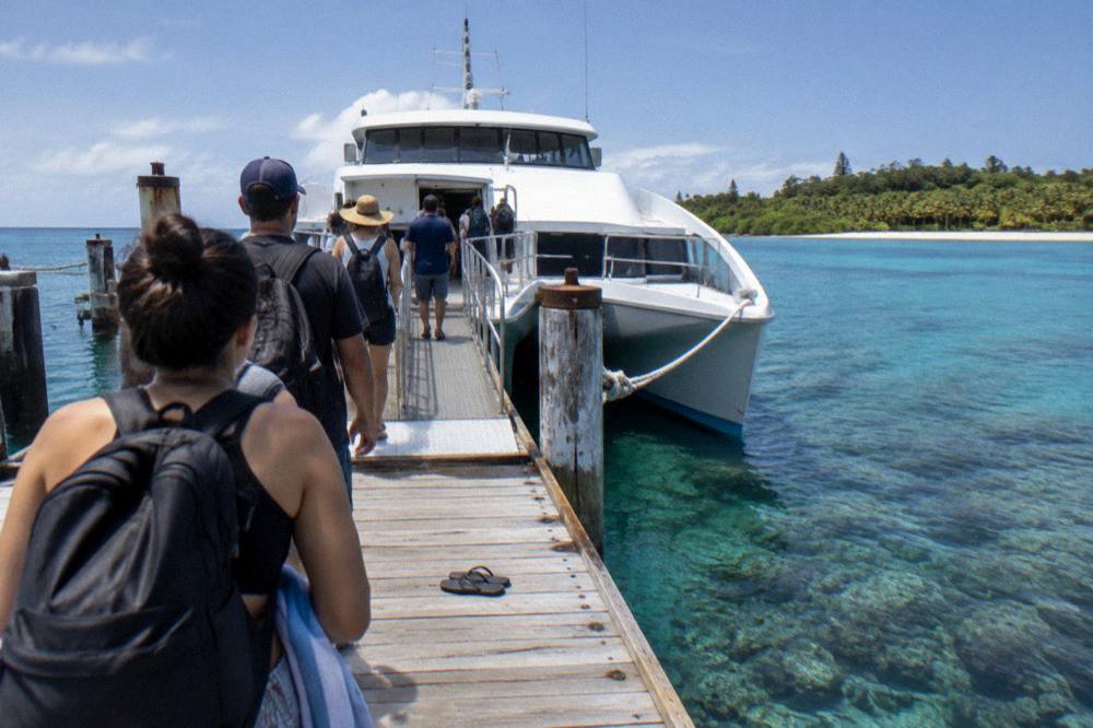 A catamaran at a tropical island jetty with passengers boarding