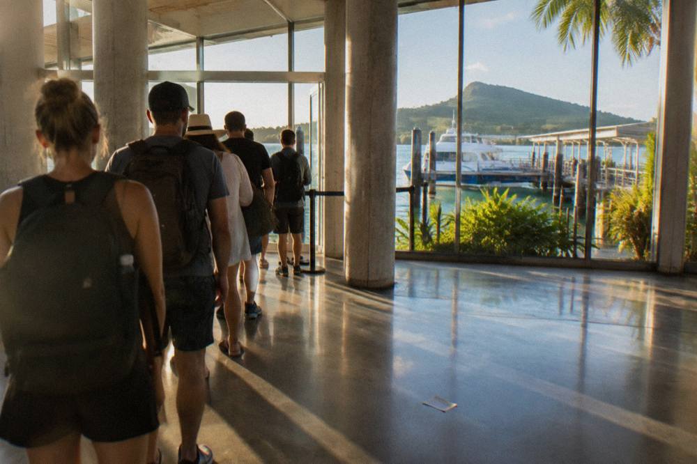 A boarding queue of day trippers at a Cairns marina terminal in morning light