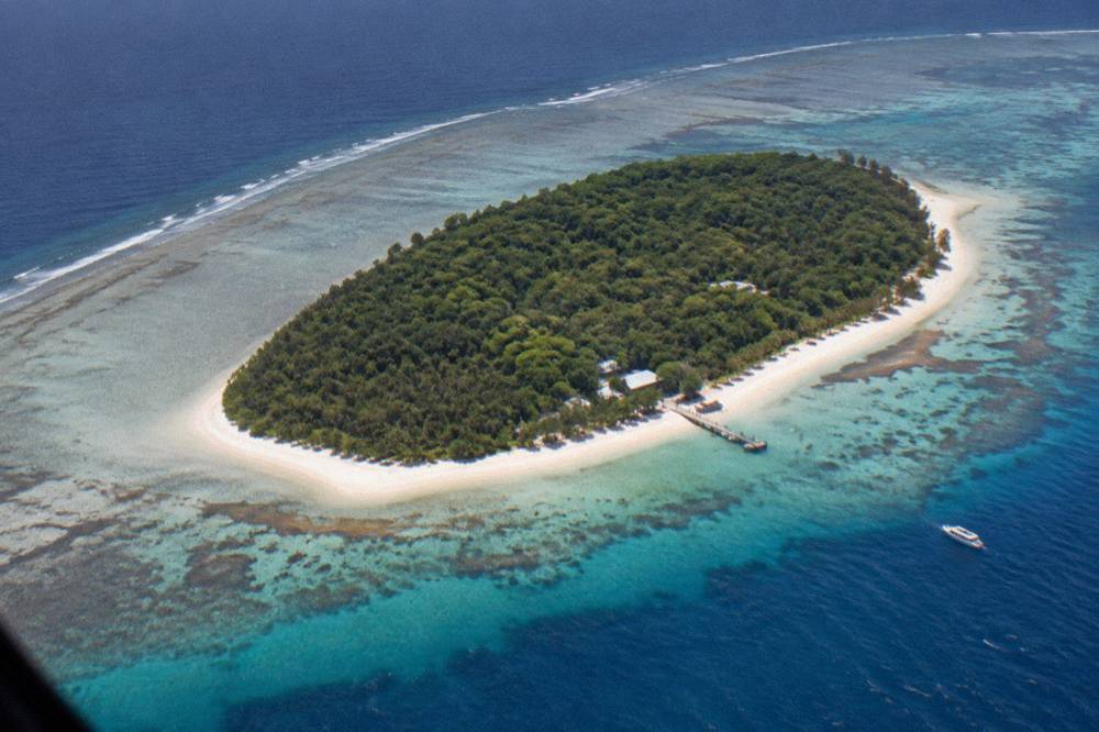 Aerial view of a coral cay surrounded by reef flats and blue ocean