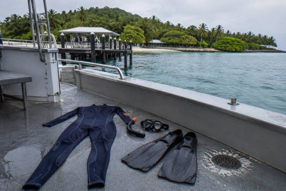 A full body lycra suit laid out on a boat deck beside snorkel gear